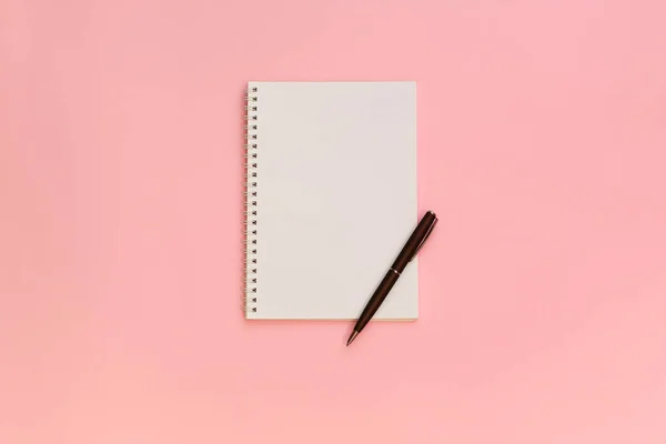 Vista superior del papel de nota en blanco con bolígrafo sobre fondo pastel rosa. Volver al concepto de escuela y educación —  Fotos de Stock