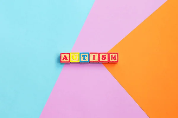 Αυτισμό πολύχρωμο λέξη από χρωματιστά ξύλινα γράμματα σε πολύχρωμο φόντο. Εικόνα ιδέας — Φωτογραφία Αρχείου