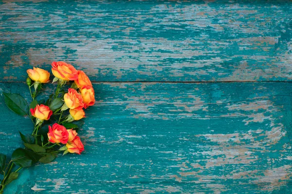 Arrière-plan d'un bouquet de belles roses fraîches orange vif pour célébrer la Saint-Valentin, anniversaire ou fête des mères sur fond de bois vert — Photo