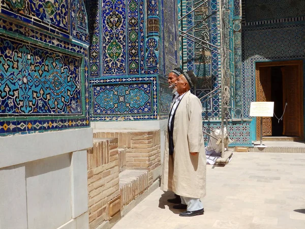 Semerkant, Özbekistan - 15 Ağustos 2018: Semerkant, Özbekistan'da Şah-ı Zinda Kutsal Mezarlığı'nın avlusunda yerel kıyafetli iki adam tarihi çinayı görüyor. — Stok fotoğraf
