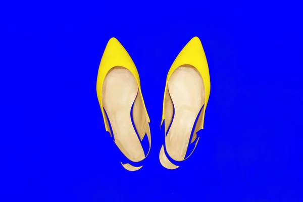 Glamor yellow fashion shoes on blue neon background. Minimal. Bright Art Colorful Style. Luxury Shiny Party lady. flat lay. — Stock Photo, Image