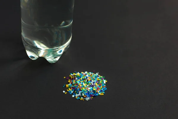 Şişedeki mikroplastik kirli su. Siyah bir arka plan üzerinde sudan çıkarılan bir mikroplastik yığını.