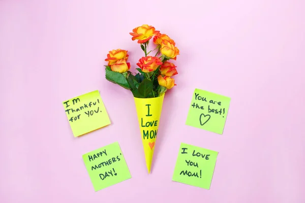 Happy Mother\'s Day note reminder yellow sticker on pink background, close up. Festive concept. I Love my Mom concept.