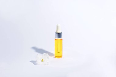 Damlalık cam Şişe Mock-Up. Beyaz arka plan, afiş veya şablon üzerinde Serum cilt bakım kozmetik ve beyaz narin çiçek. Güzellik ürün konsepti.