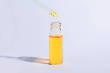 Pipetli kozmetik veya tıbbi şişe. Beyaz arka plan üzerinde damlalık ile cam şişe altın sıvı ürün. Güzellik konsepti. Afiş