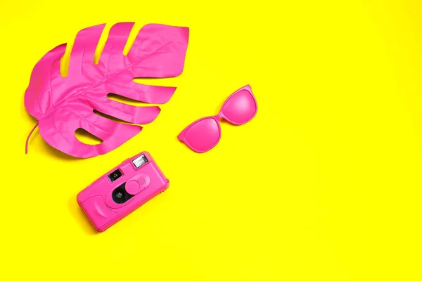 Foglia di palma tropicale rosa di monstera, occhiali da sole e macchina fotografica su sfondo giallo. concetto di moda. minimalismo. Concetto estivo. Arte concettuale . — Foto Stock