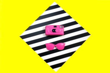 Renkli arka plan üzerinde boyalı pembe Moda güneş gözlüğü ve kamera. Geometri kavramı, minimalizm. Pop Art.