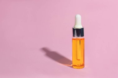 Damlalık cam Şişe Mock-Up. Pembe arka plan, afiş veya şablon serum cilt bakım kozmetik. Güzellik ürün konsepti.