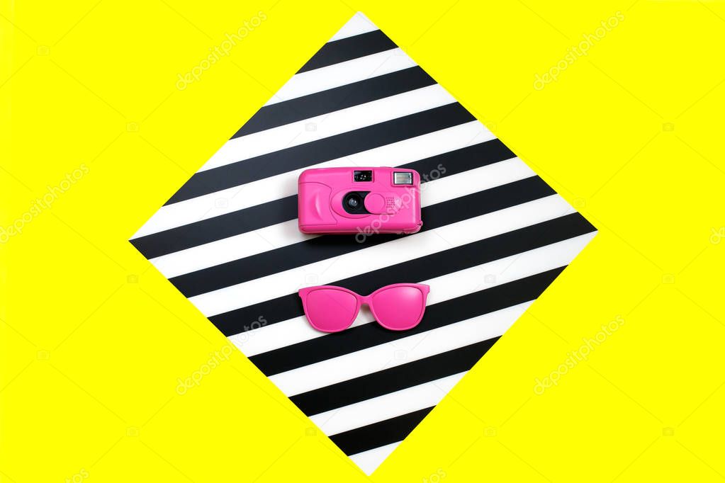Painted pink Fashion sunglasses and camera on colorful background. Geometry concept, minimalism. Pop Art.
