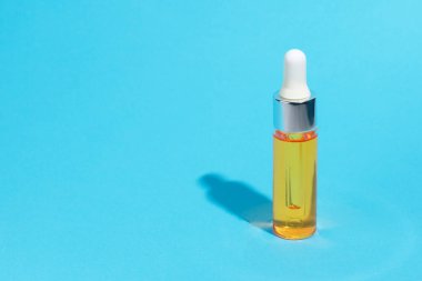 Damla cam şişe mock-up. Mavi arka plan, afiş veya şablon üzerinde Serum Cilt Bakımı kozmetik. Güzellik ürün konsepti.