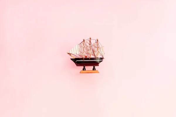 Small toy wooden ship on pink background. Sailing ship model