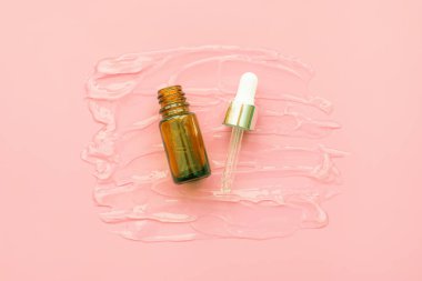Serum damlaları ya da pembe arka planda pipeti olan sıvı jel. Cilt bakımı ve hijyen için kozmetik ürünleri.