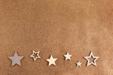 Gül sarısı yıldızlar ve açık kahverengi arka planda parıltı. Tatil partisi dekorasyonu. Yeni yıl kutlaması.