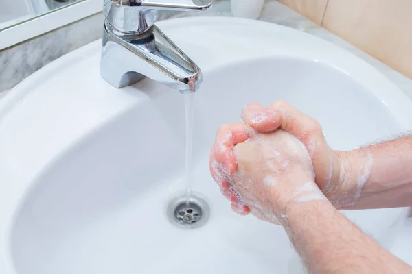 Homem lavar as mãos com sabão sob pia do banheiro . — Fotografia de Stock