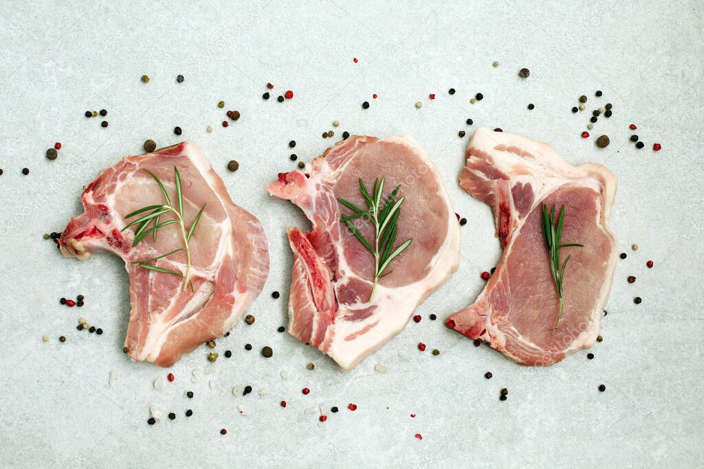 Raw pork steak on bone on light background. Raw pork steak with herbs and spices. Cooking meat. Top view