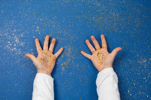 Childs manos sosteniendo estrellas doradas sobre fondo azul brillante. — Foto de Stock
