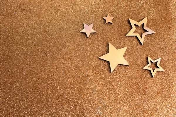 Rose gold stars and glitter on light brown background. Holiday party decoration. New year celebration.