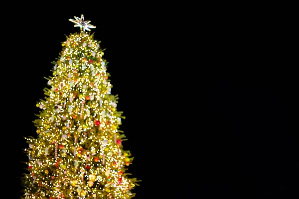Ofokuserad julgran med ljus dekorationer utomhus på natten. — Stockfoto