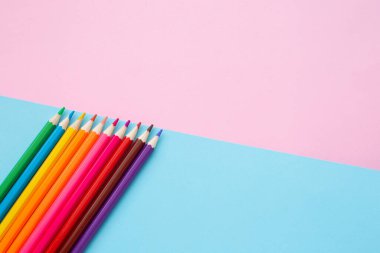 Mavi ve pembe arka planda renkli kalemler. Okul ve ofis aksesuarları. Okul konsepti. düz yatay üst görünüm kopyalama alanı