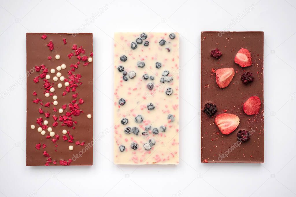 Handmade milk and white chocolate bars with a variety of dried fruit toppings. Top view.