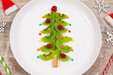 Tahta masadaki kivi dilimlerinden yapılmış Noel ağacı. Noel kahvaltısı için yaratıcı bir fikir ya da çocuklar için yeni yıl şenlikli tatlılar. Üst görünüm.