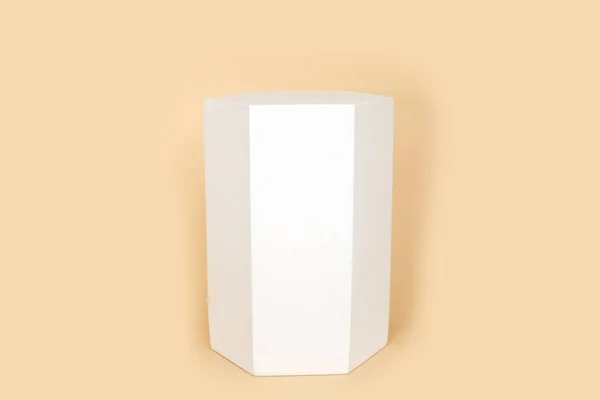 パステルベージュの色の背景に形をキャスト白い色で高精度プリズム幾何学的図形 六角形の形をした側面を持つ三次元形状 幾何学的表彰台 ファッション雑誌 — ストック写真