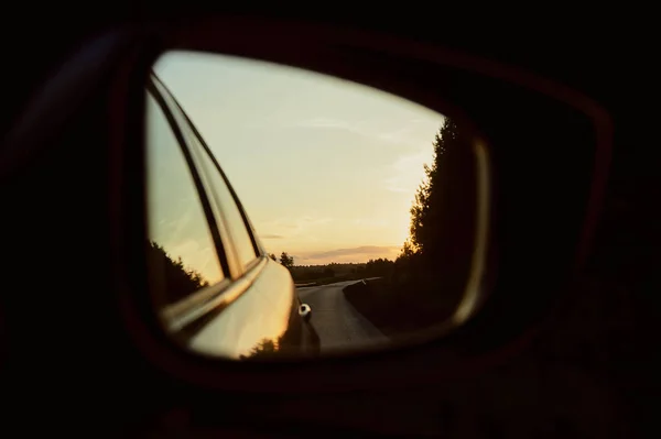 Reflection of the evening highway in the rearview mirror.