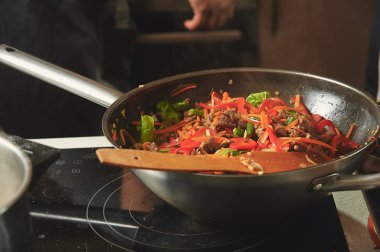 Bir tavada taze pişmiş wok erişte hizmet bekleyen bir tabak üzerinde duruyor.