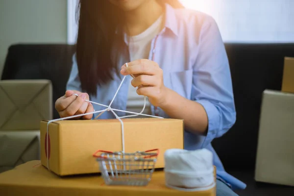Young entrepreneur packing parcel box and work at home. New generation life style concept.