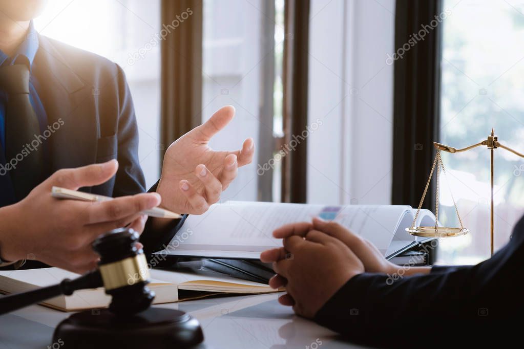 Business woman and lawyers discussing contract papers with brass scale on wooden desk in office. Law, legal services, advice, Justice concept.