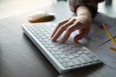 İş kadını, klavye ve masaüstü bilgisayarını ahşap masa, vergi, muhasebe, istatistik ve analitik araştırma kavramında matematik finansmanı için kullanıyor.