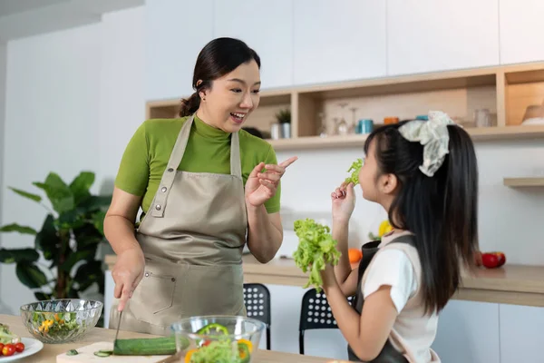 Bir anne kızıyla taze sebzeleri paylaşır sağlıklı yeme alışkanlıklarını ve neşeli yemek pişirme deneyimlerini teşvik eder..