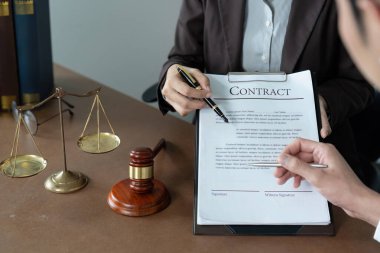 Bir avukat, profesyonel bir ortamda netlik ve anlayış sağlamak amacıyla bir müşteriyle sözleşme detaylarını tartışır..