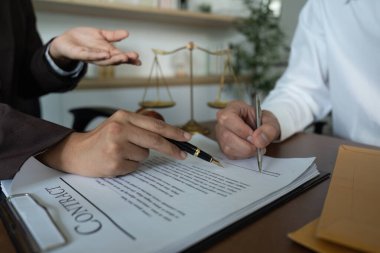 Bir avukat, sözleşmenin kilit kısımlarını belirtirken, müvekkil de imzalamaya hazırlanıyor..