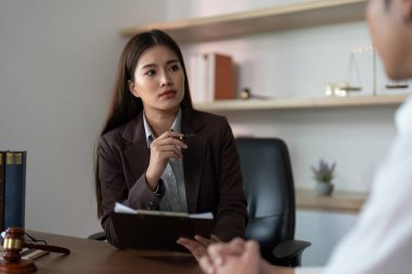 Odaklanmış bir avukat, modern ofis ortamında yasal konuları tartışan bir müvekkil ile temas kurar. Profesyonellik ve güvene vurgu.