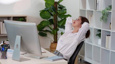 Genç bir profesyonel, uzak çalışma süresince sağlığını ve verimliliğini arttırmak için ofis masasına uzanır..
