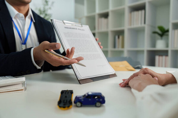 Страховой агент представляет клиенту страховой документ, подчеркивающий ключевые условия покрытия транспортных средств.