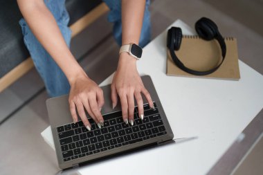 Uzaktan çalışma ve dijital bağlanma detaylarını vurgulayan, dizüstü bilgisayarda yazı yazan bir kadının yakın çekim görüntüsü.