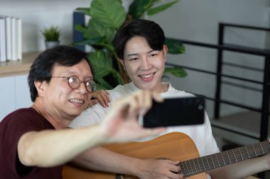 Arkadaşlar gitarın keyfini çıkarırken selfie çekiyorlar. Neşeli bağlantılarını vurguluyorlar..