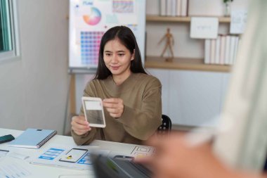 Bir tasarımcı UI UX tasarım oturumunda yaratıcılığı ve takım çalışmasını vurgulayan bir akıllı telefon prototipi sunar.