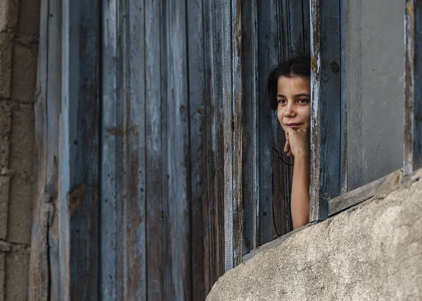 eski köy evinin penceresinden bakan küçük kız