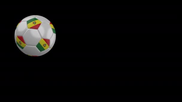 Balón de fútbol con bandera de Bolivia vuela más allá de la cámara, cámara lenta, canal alfa — Vídeos de Stock