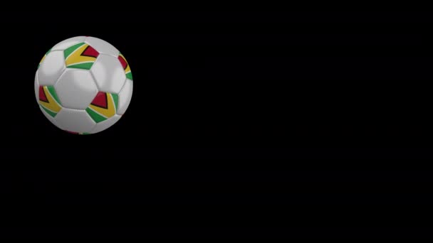 Balón de fútbol con bandera de Guyana vuela más allá de la cámara, cámara lenta, canal alfa — Vídeos de Stock