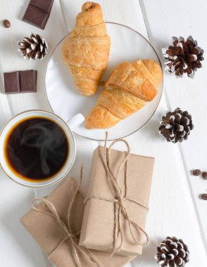 Beyaz fincan sıcak kahve çift ayçöreği ve çikolata. Beyaz ahşap zemin.