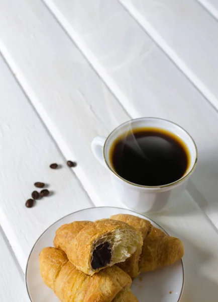 Taza blanca de café caliente con un par de croissants y chocolate . — Foto de Stock