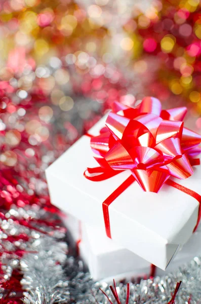 Christmas gift box with red ribbons on white table and decoration. — Stock Photo, Image