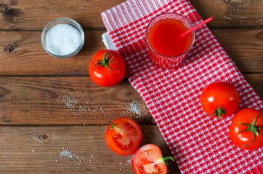 Taze domates ve tuz ile bardak domates suyu. Rustik ahşap arka plan.