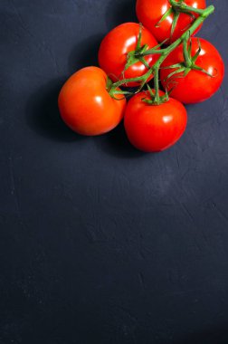 Olgun kırmızı domates karanlık taş zemin üzerine.