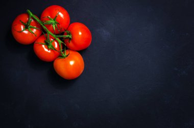 Olgun kırmızı domates karanlık taş zemin üzerine.