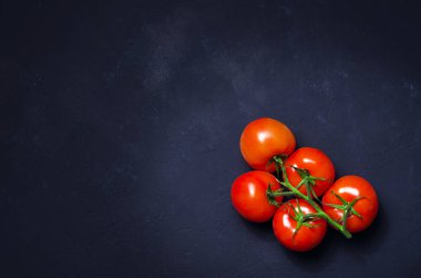 Olgun kırmızı domates karanlık taş zemin üzerine.